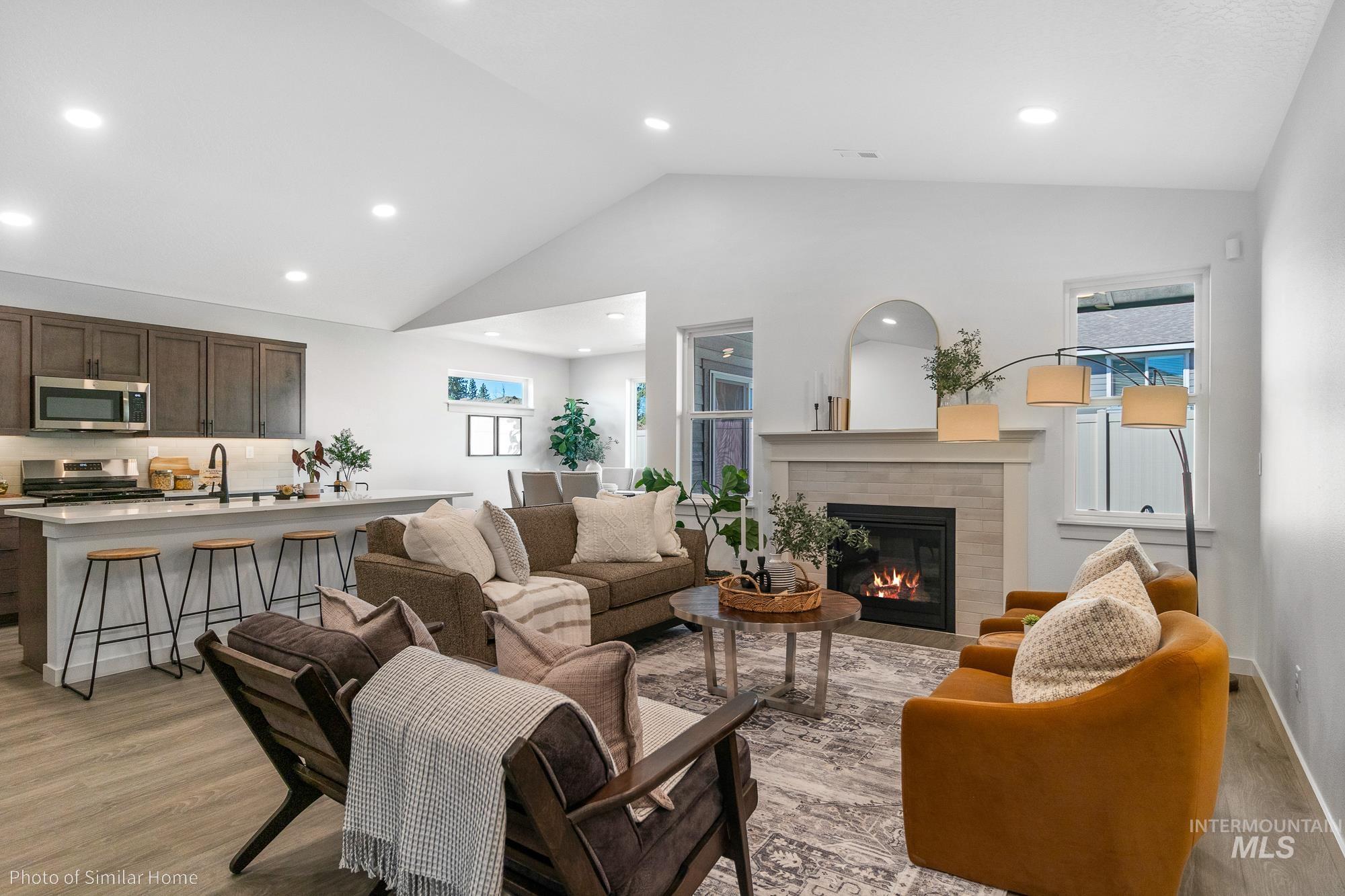 Living room with light wood-style flooring, recessed lighting, a brick fireplace, and high vaulted ceiling