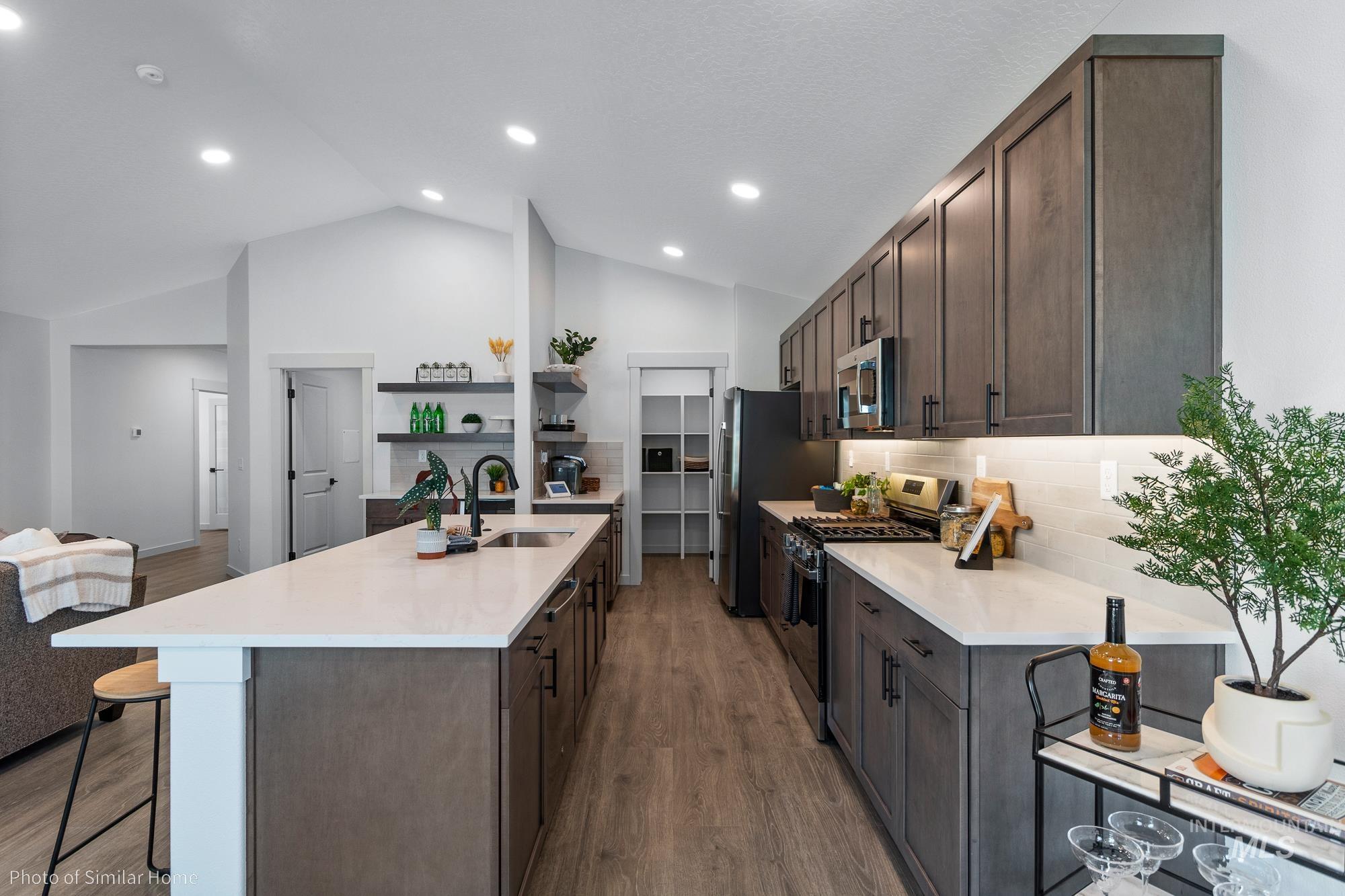 Kitchen featuring dark brown cabinets, decorative backsplash, stainless steel appliances, a breakfast bar, and lofted ceiling
