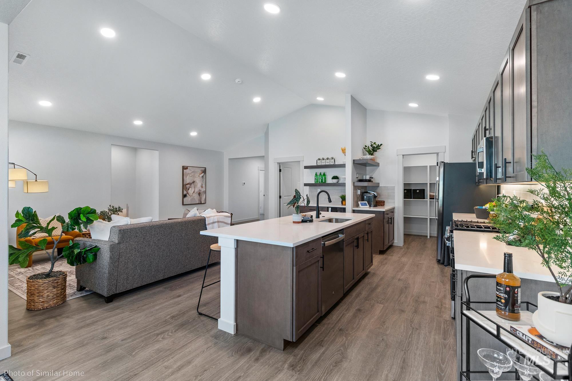 Kitchen featuring a kitchen breakfast bar, light wood-type flooring, a kitchen island with sink, light stone countertops, and open floor plan