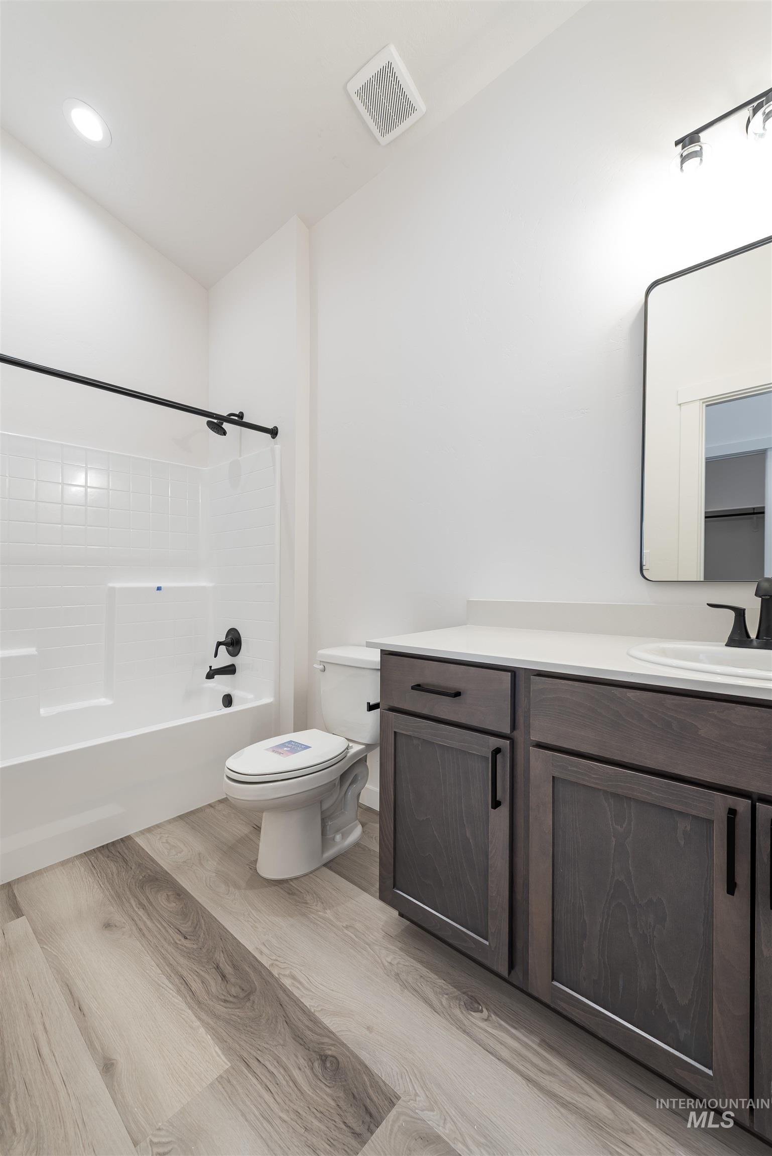 Bathroom with vanity, shower / washtub combination, and light wood-style flooring