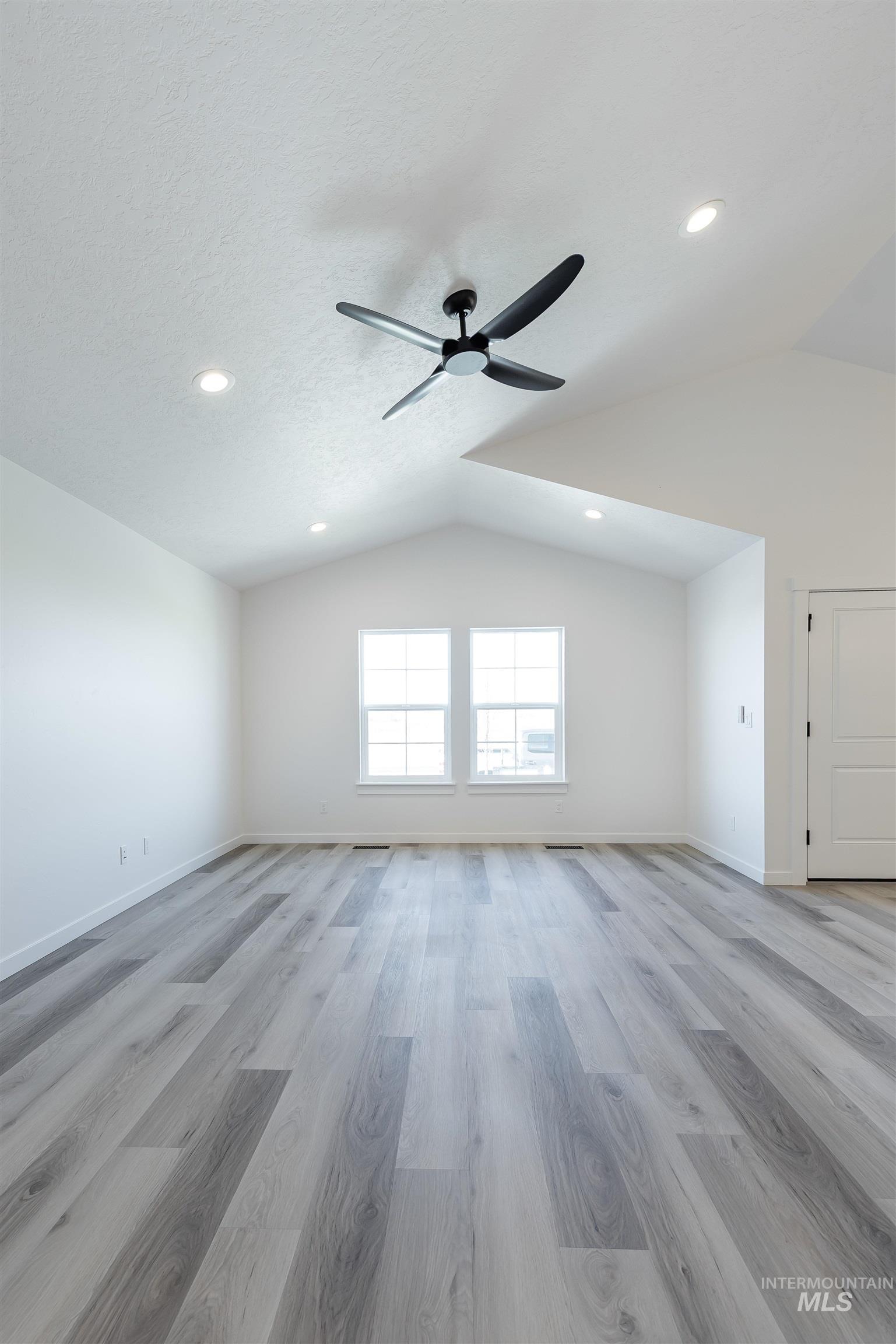 Empty room with vaulted ceiling, light wood-style floors, ceiling fan, and recessed lighting