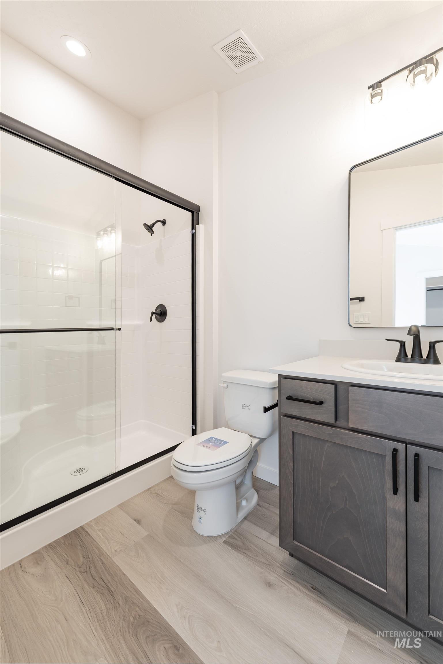 Bathroom with vanity, light wood-type flooring, and a shower stall