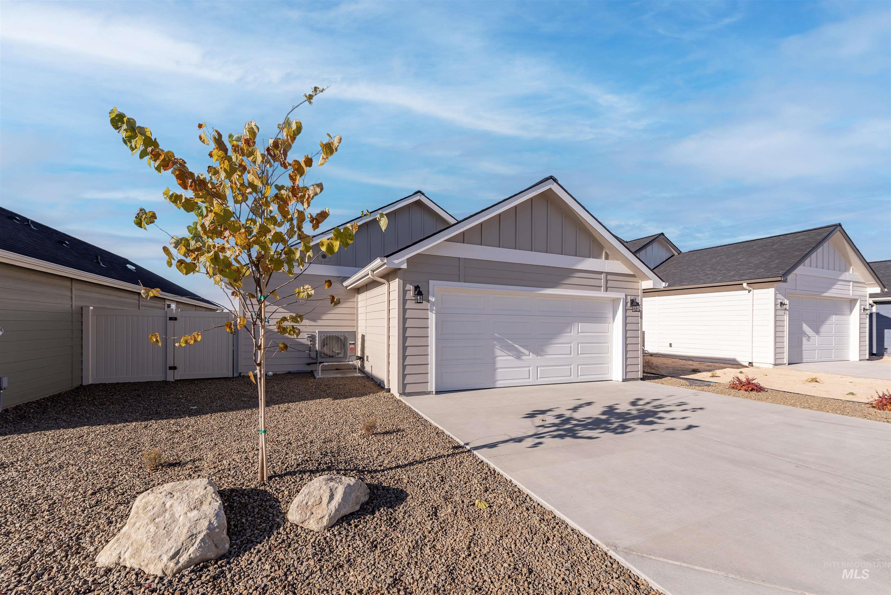 Ranch-style home featuring board and batten siding, driveway, a gate, and a garage