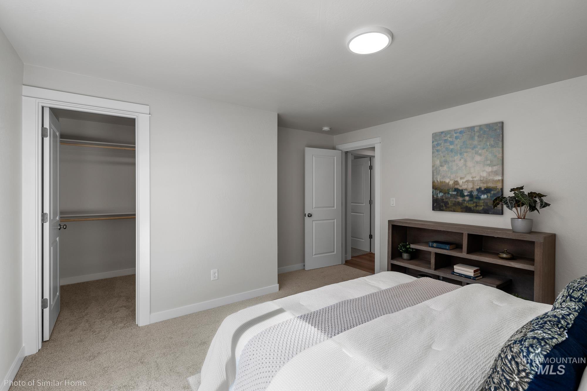 Bedroom with light carpet and a walk in closet