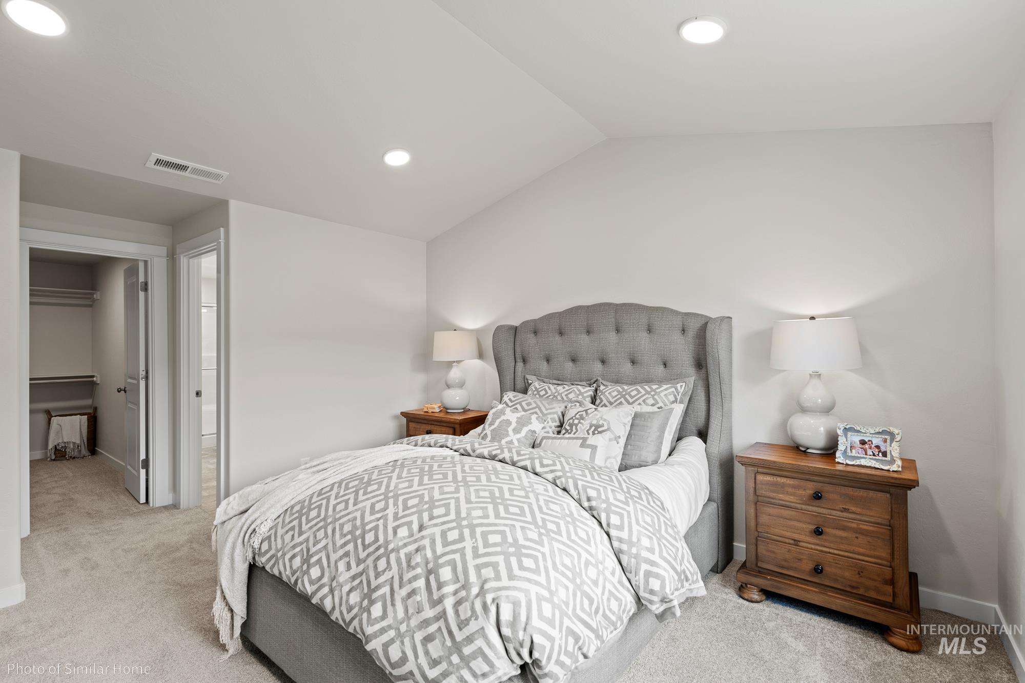 Carpeted bedroom with a spacious closet, recessed lighting, and lofted ceiling