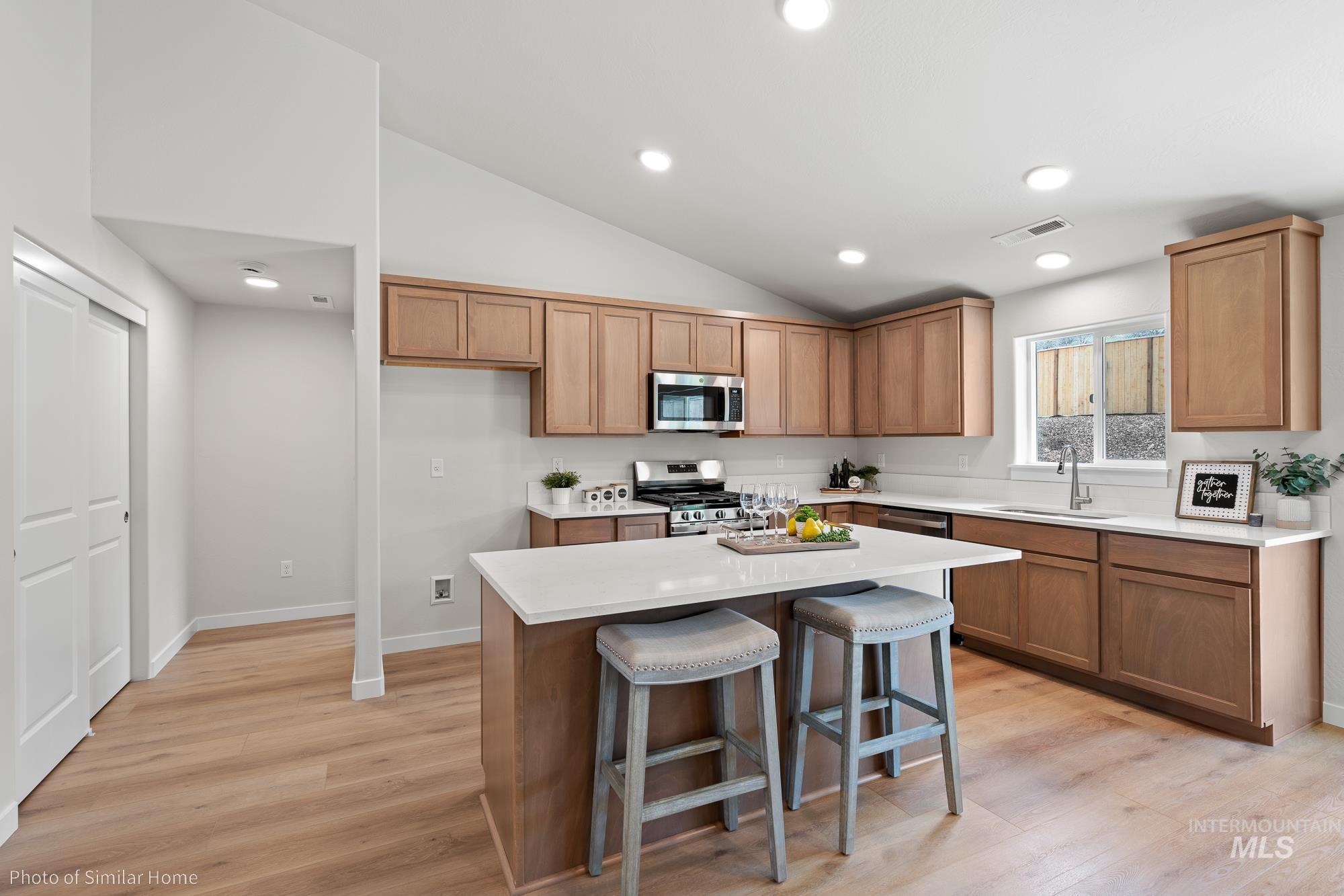Kitchen featuring a breakfast bar area, light wood-type flooring, a kitchen island, lofted ceiling, and recessed lighting