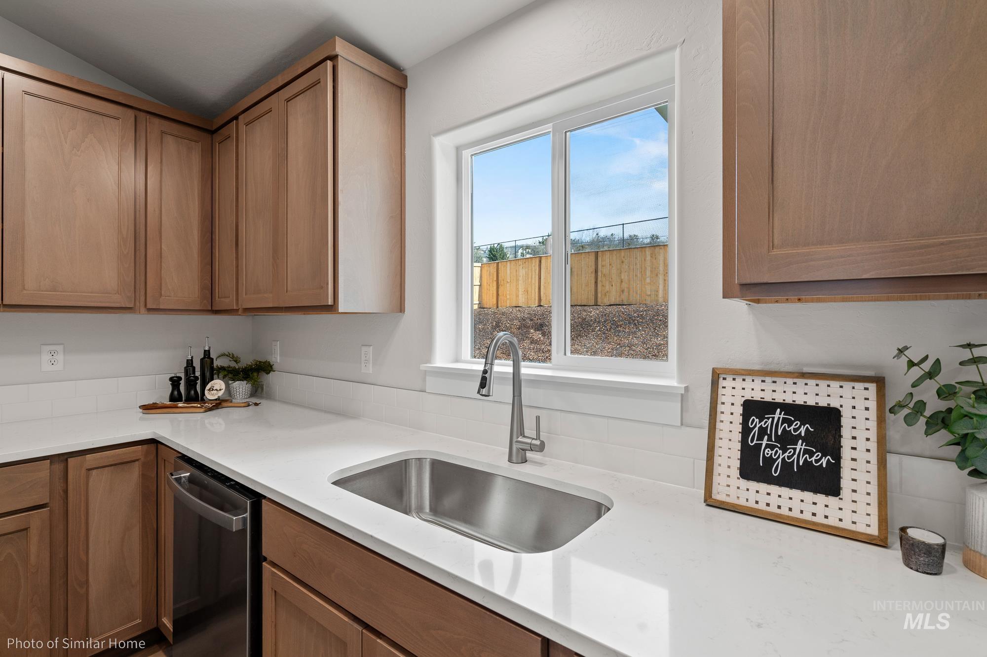 Kitchen featuring dishwasher, light stone counters, and brown cabinetry