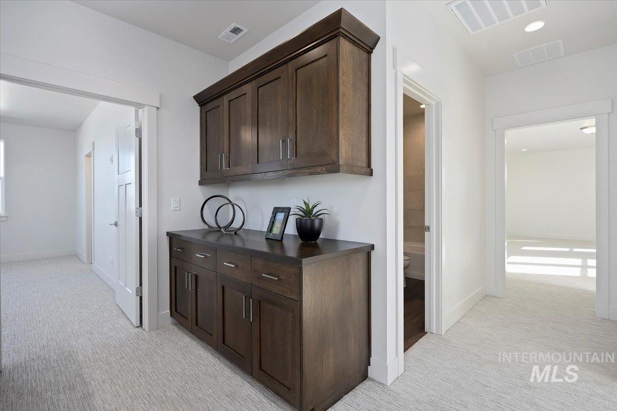 Top stairs landing featuring dark brown quarter sawn oak cabinets, light colored carpet.