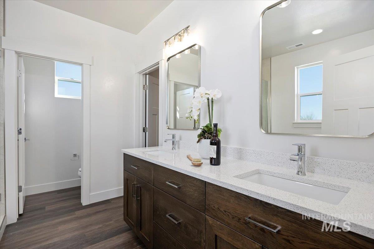 Primary Bathroom with double vanity and dark wood-type flooring