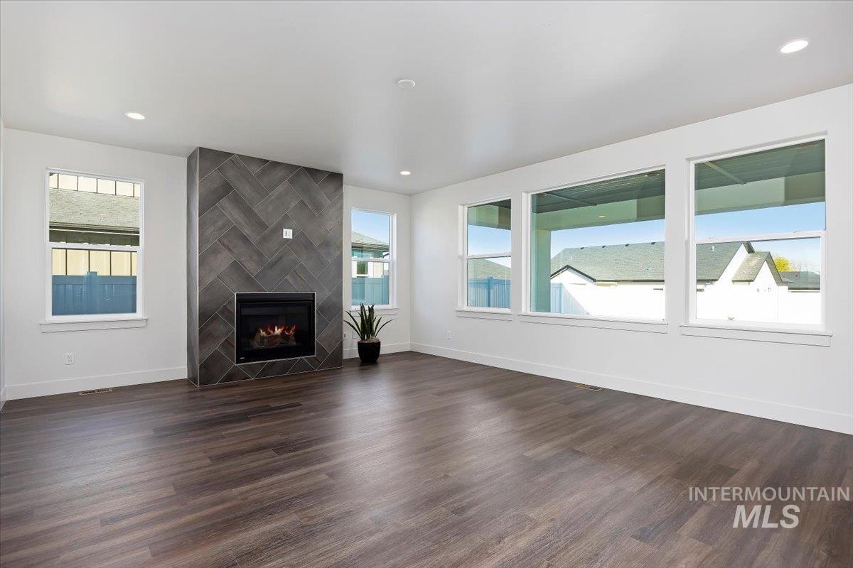 Unfurnished living room featuring a tile fireplace, dark wood-style flooring, and recessed lighting