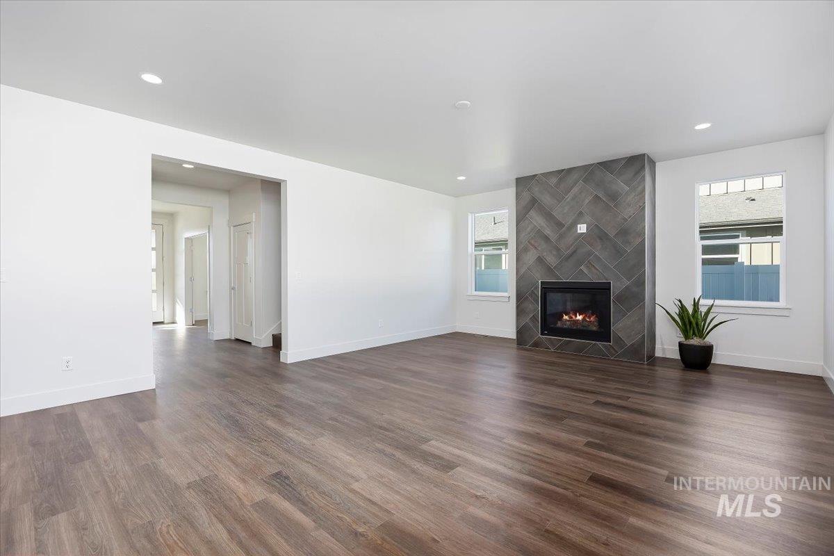 Unfurnished living room featuring dark wood finished floors, recessed lighting, and a tile fireplace