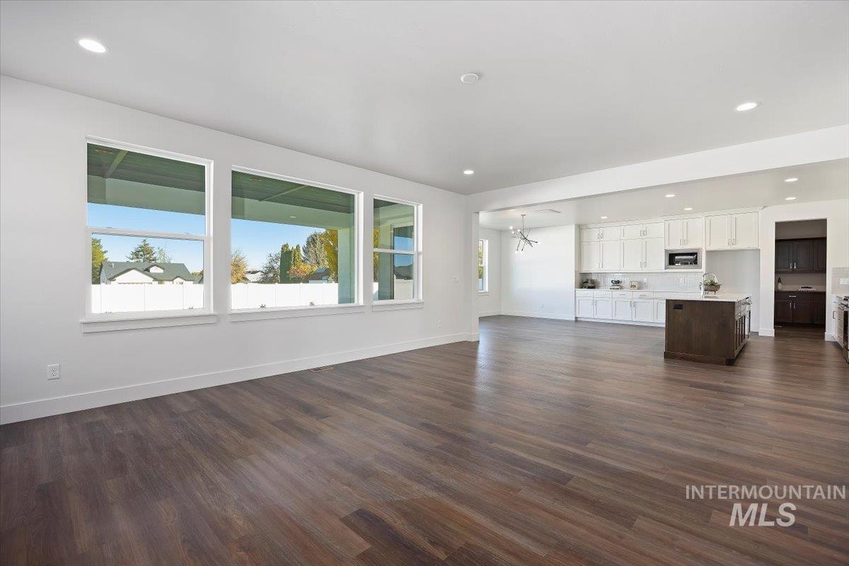 Unfurnished living room featuring recessed lighting, dark wood-type flooring, and a chandelier