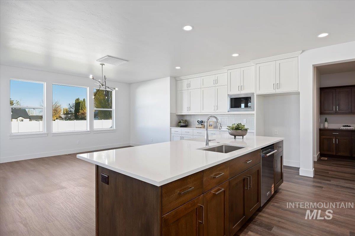 Kitchen featuring white cabinets, dark wood finished floors, decorative backsplash, dark brown cabinets, and recessed lighting
