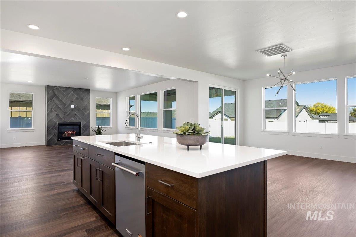 Kitchen with open floor plan, dark brown cabinetry, a fireplace, dark wood-style flooring, and dishwasher