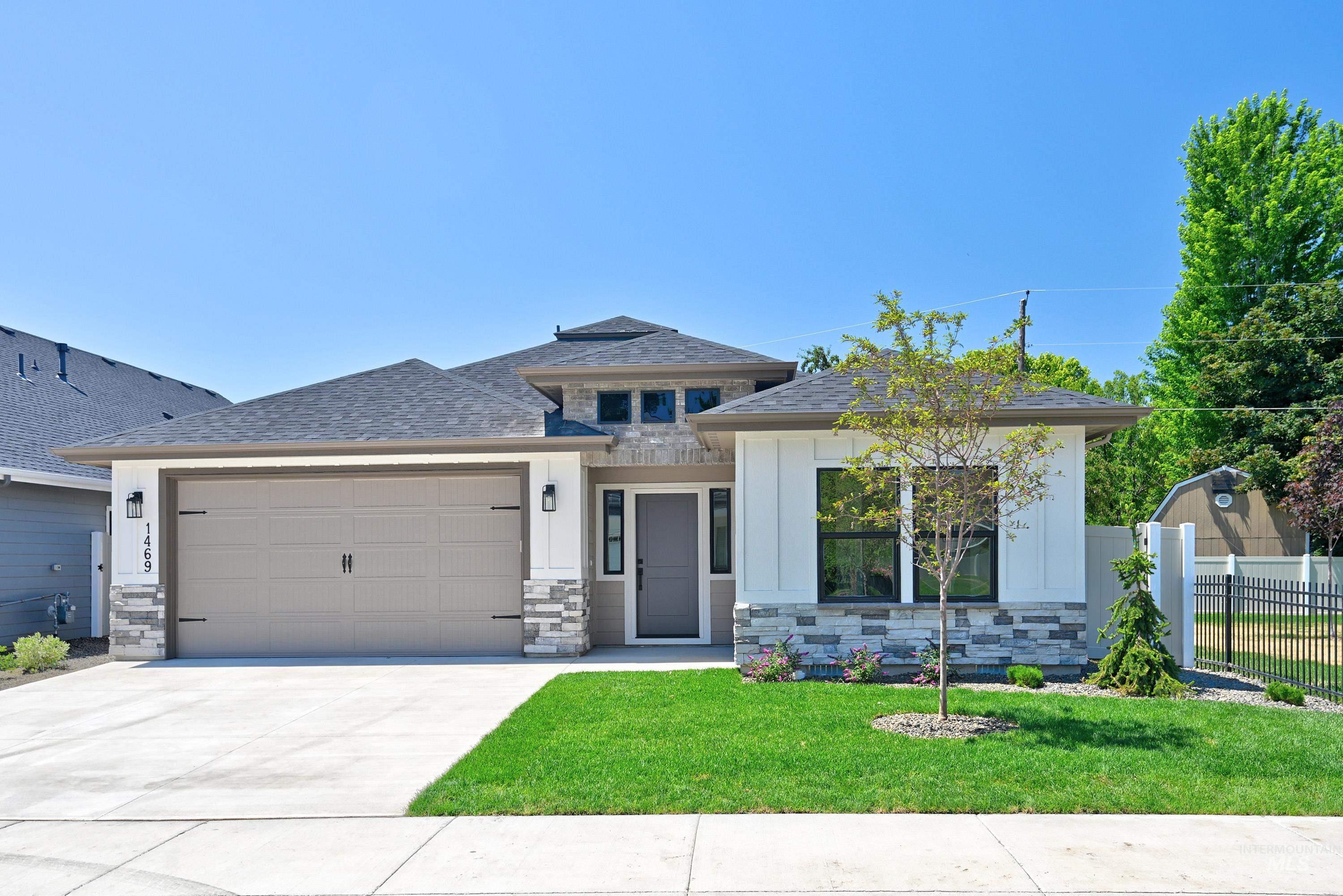 Prairie-style home with a garage, stone siding, concrete driveway, a shingled roof, and board and batten siding