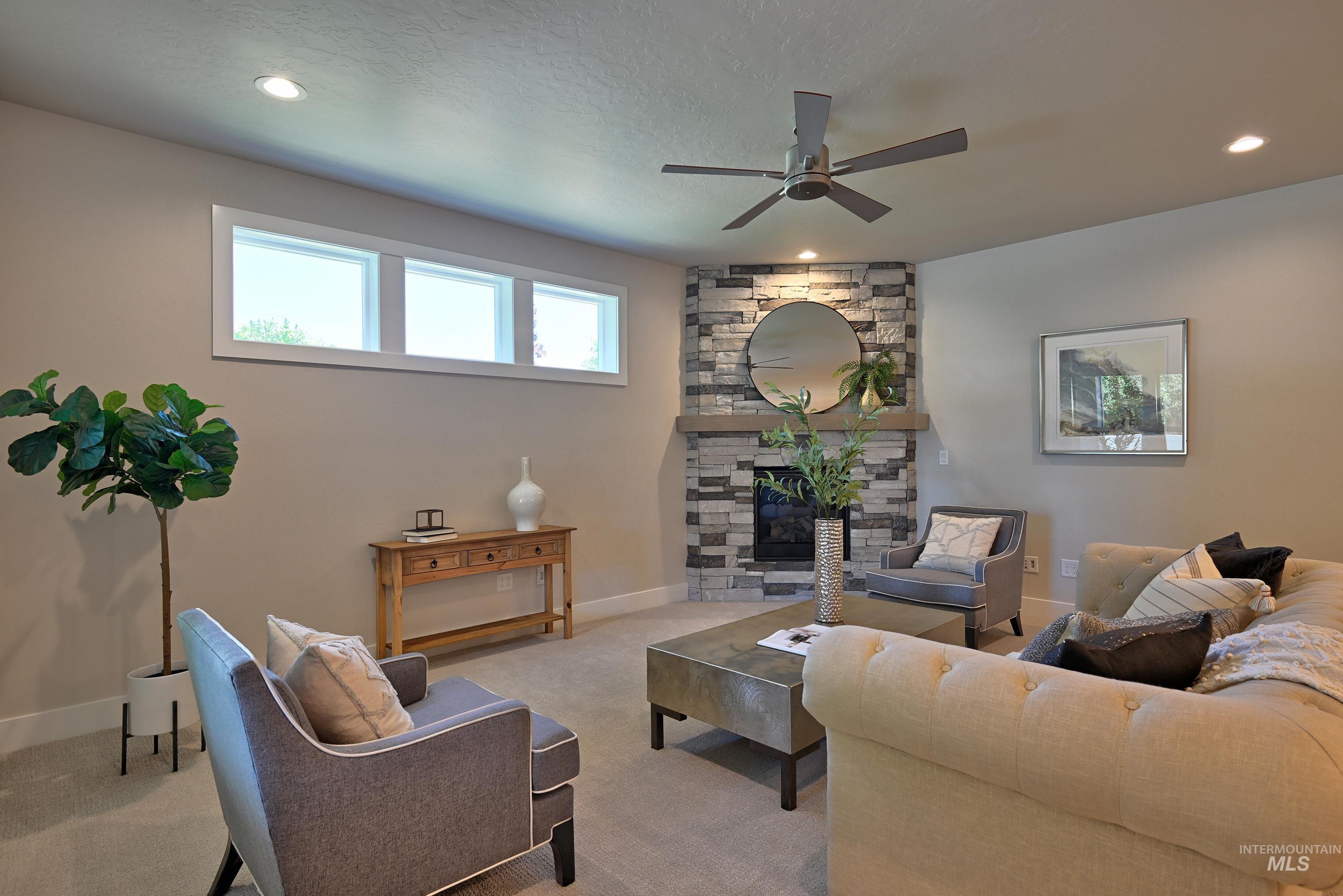 Living area with ceiling fan, light colored carpet, a stone fireplace, and recessed lighting