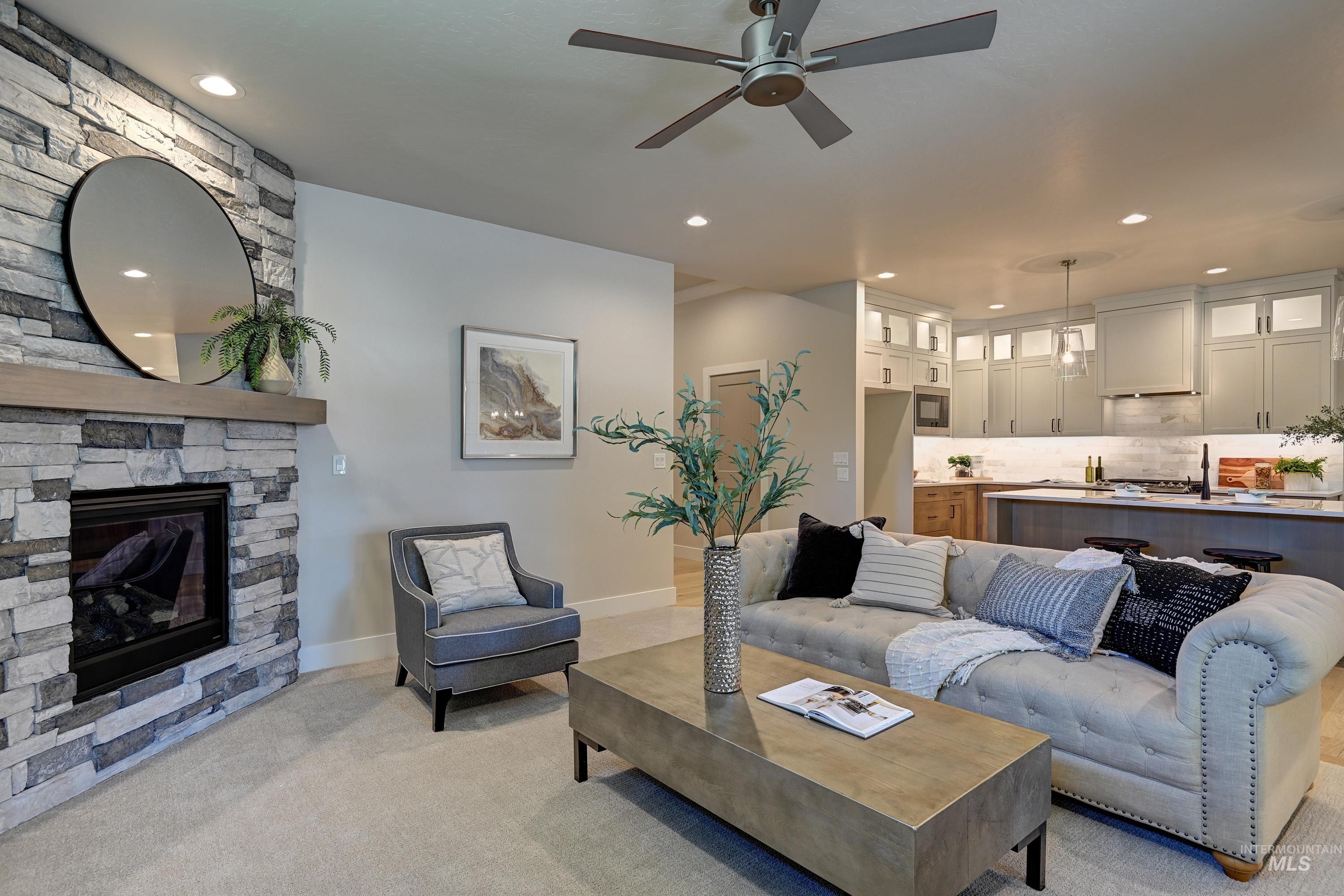 Living room featuring light carpet, a ceiling fan, a stone fireplace, and recessed lighting