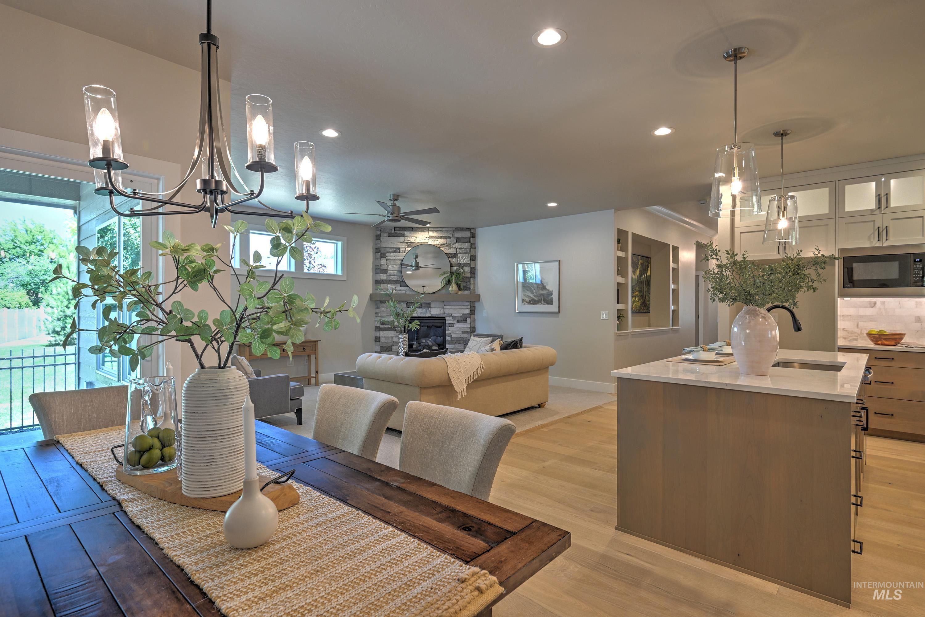 Dining area with a ceiling fan, a fireplace, light wood finished floors, recessed lighting, and a chandelier