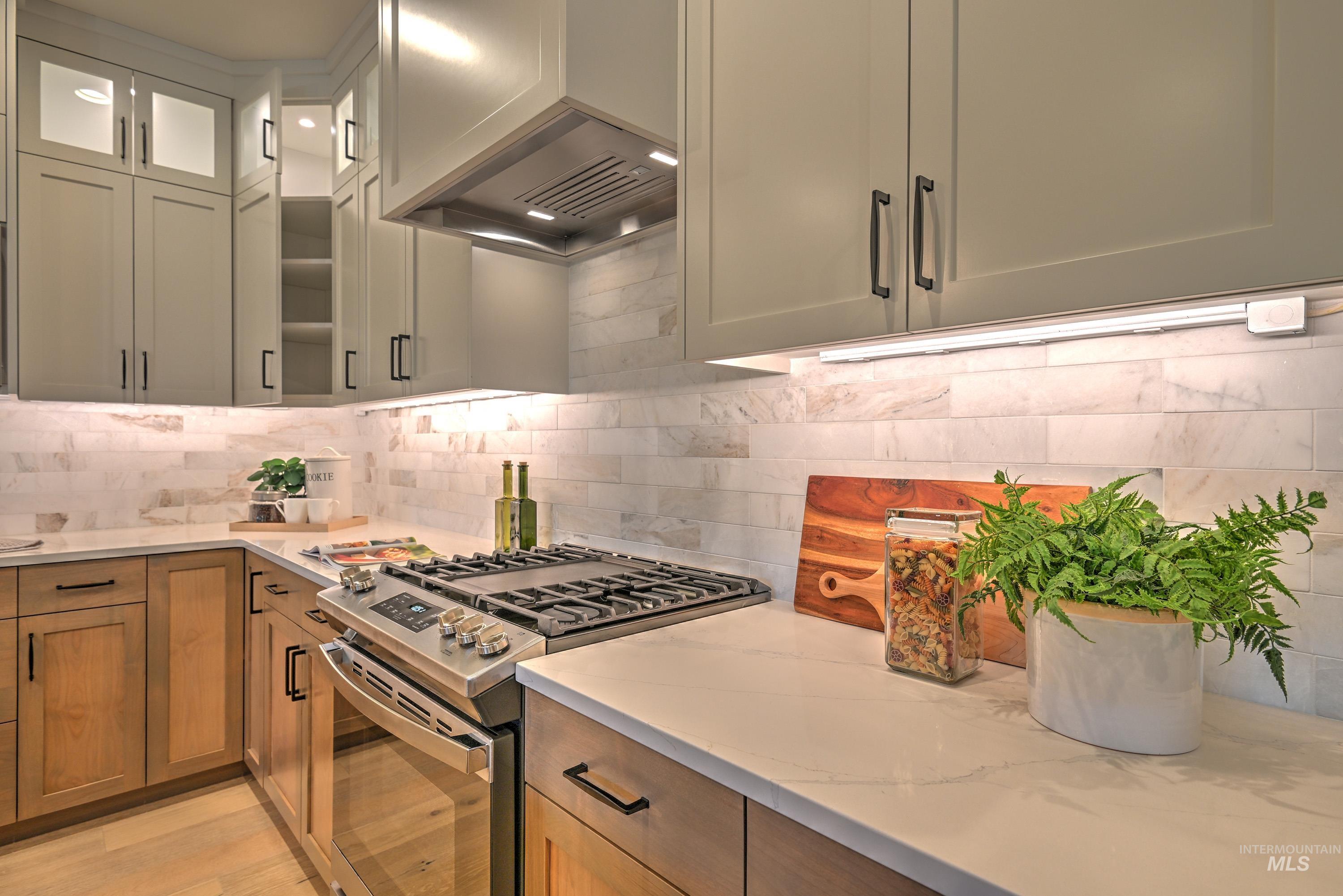 Kitchen with stainless steel gas range, Quartz counters, wall chimney range hood, and decorative backsplash