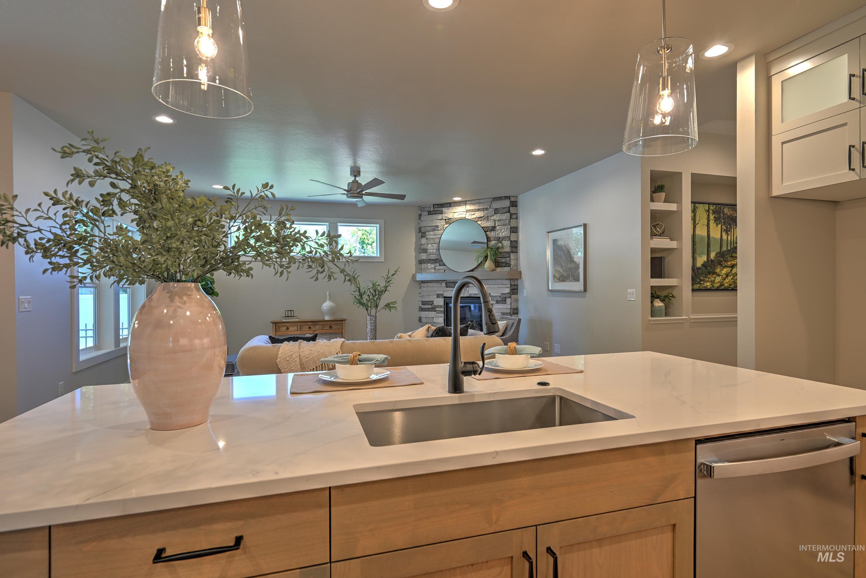 Kitchen with stainless steel dishwasher, open floor plan, recessed lighting, a stone fireplace, and light stone countertops