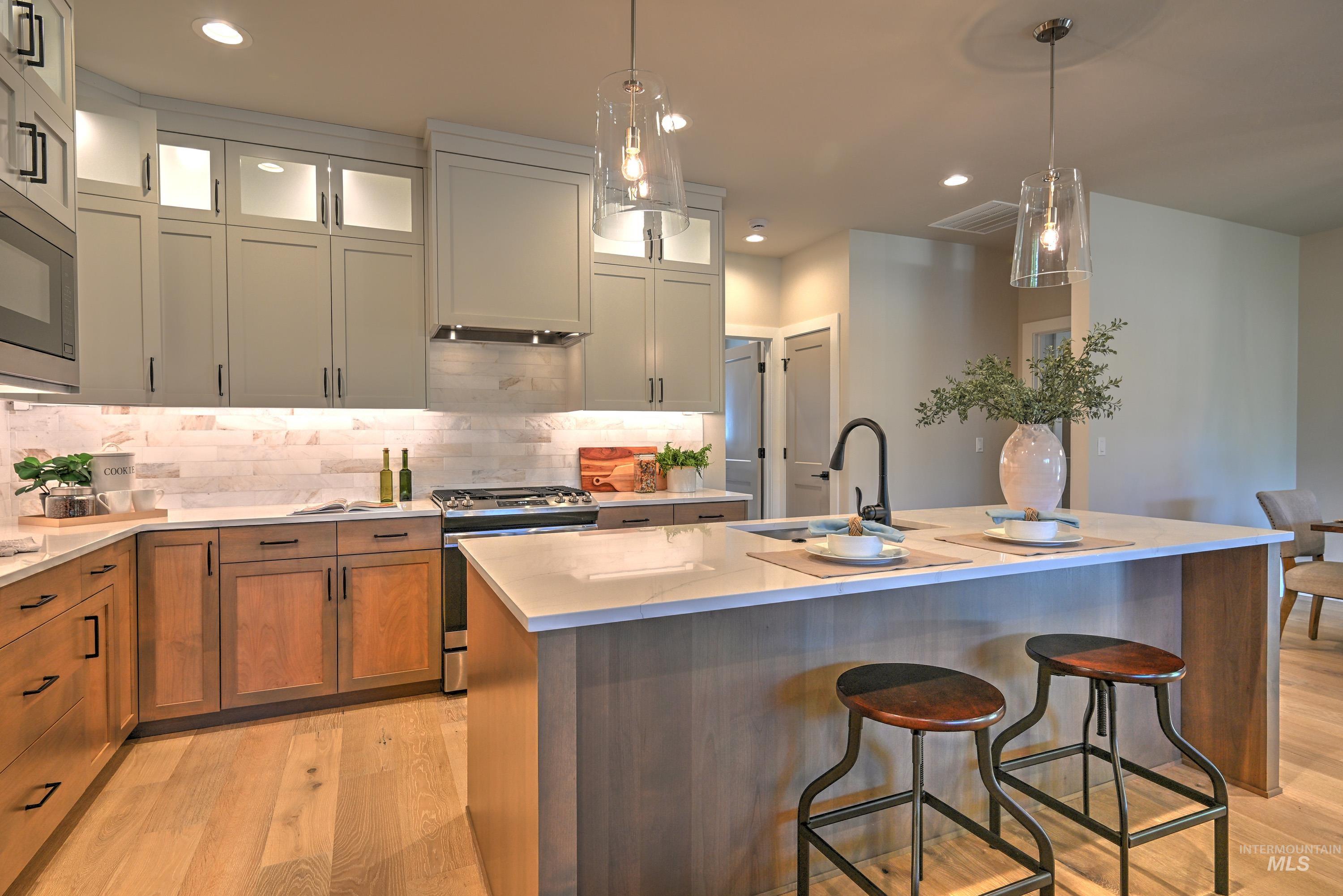 Kitchen with appliances with stainless steel finishes, light wood finished floors, tasteful backsplash, recessed lighting, and a kitchen breakfast bar