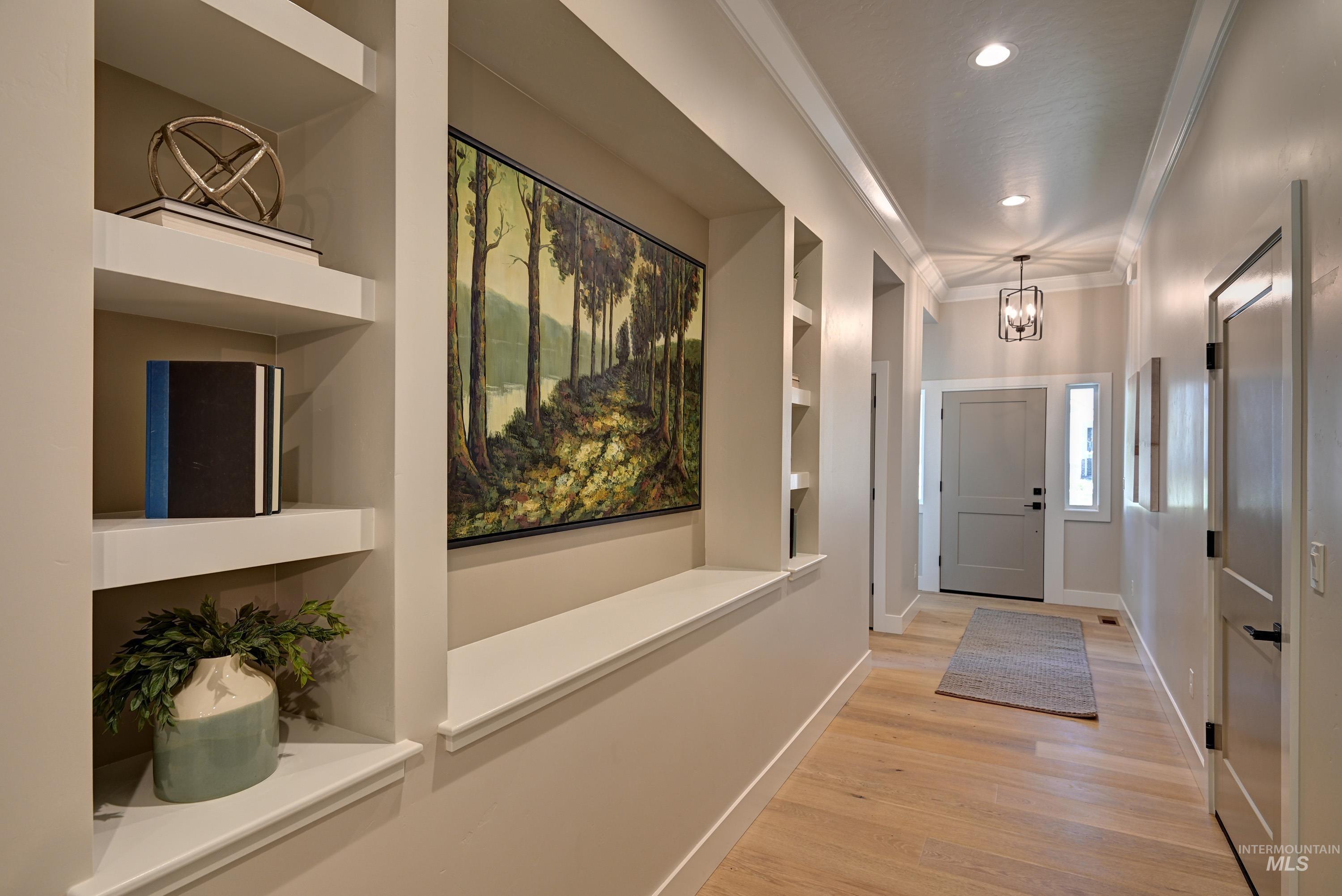 Foyer entrance featuring a chandelier, crown molding, light wood-style flooring, and recessed lighting