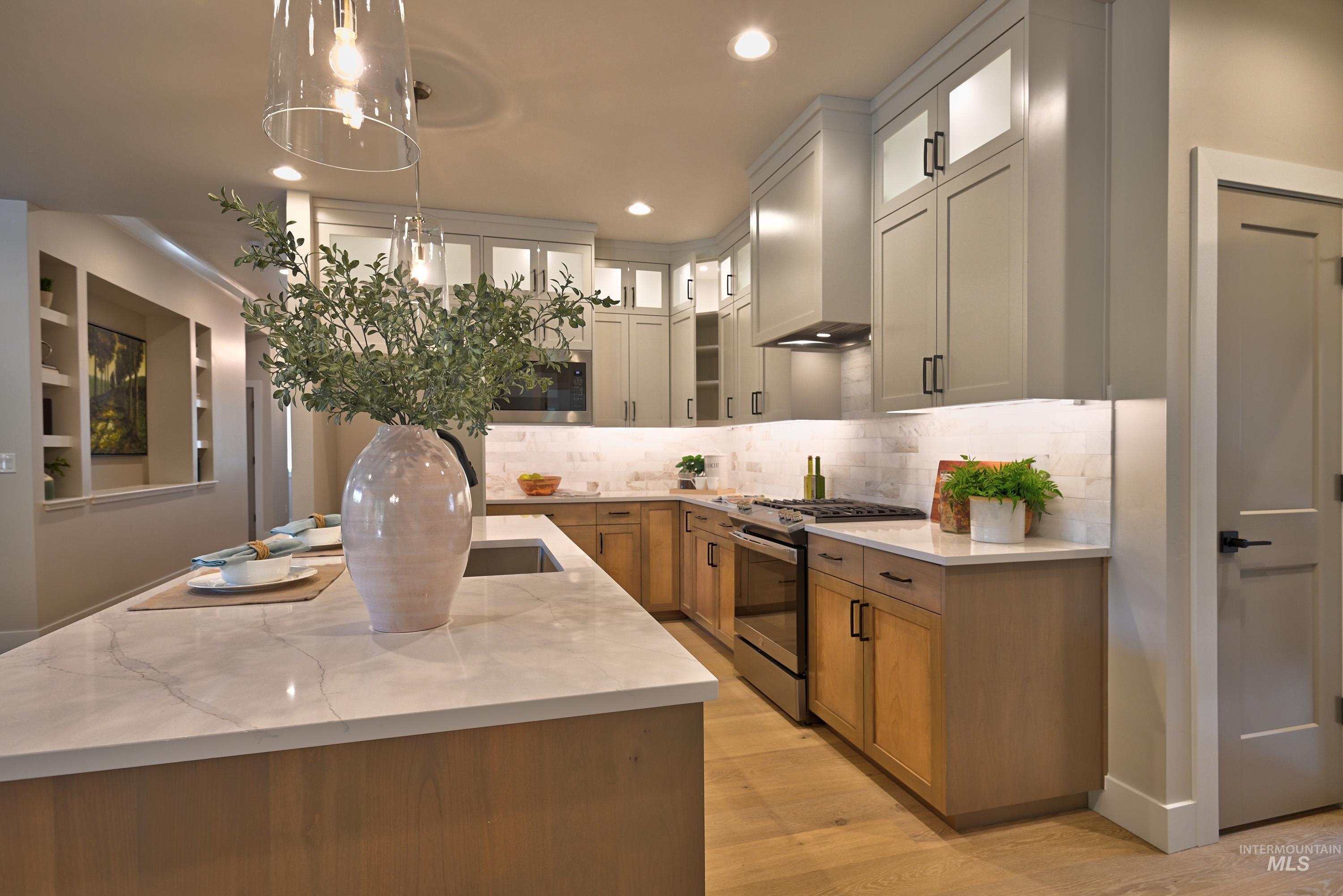 Kitchen featuring stainless steel range with gas stovetop, decorative backsplash, light wood finished floors, wall chimney range hood, and recessed lighting