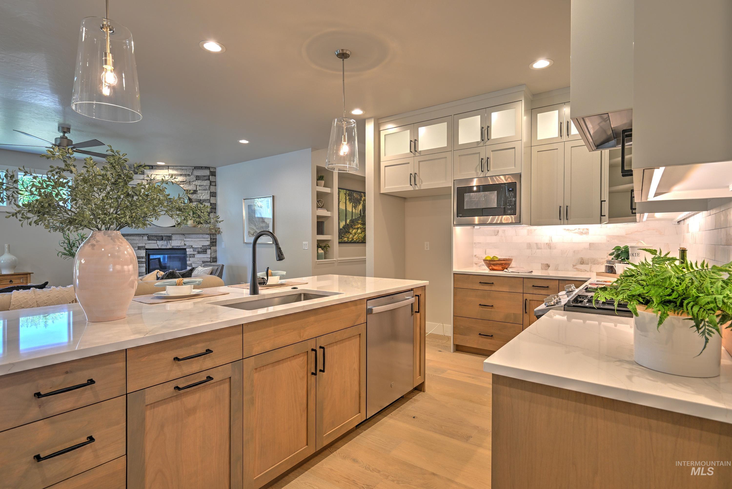 Kitchen with open floor plan, light stone counters, light wood-type flooring, a ceiling fan, and dishwasher