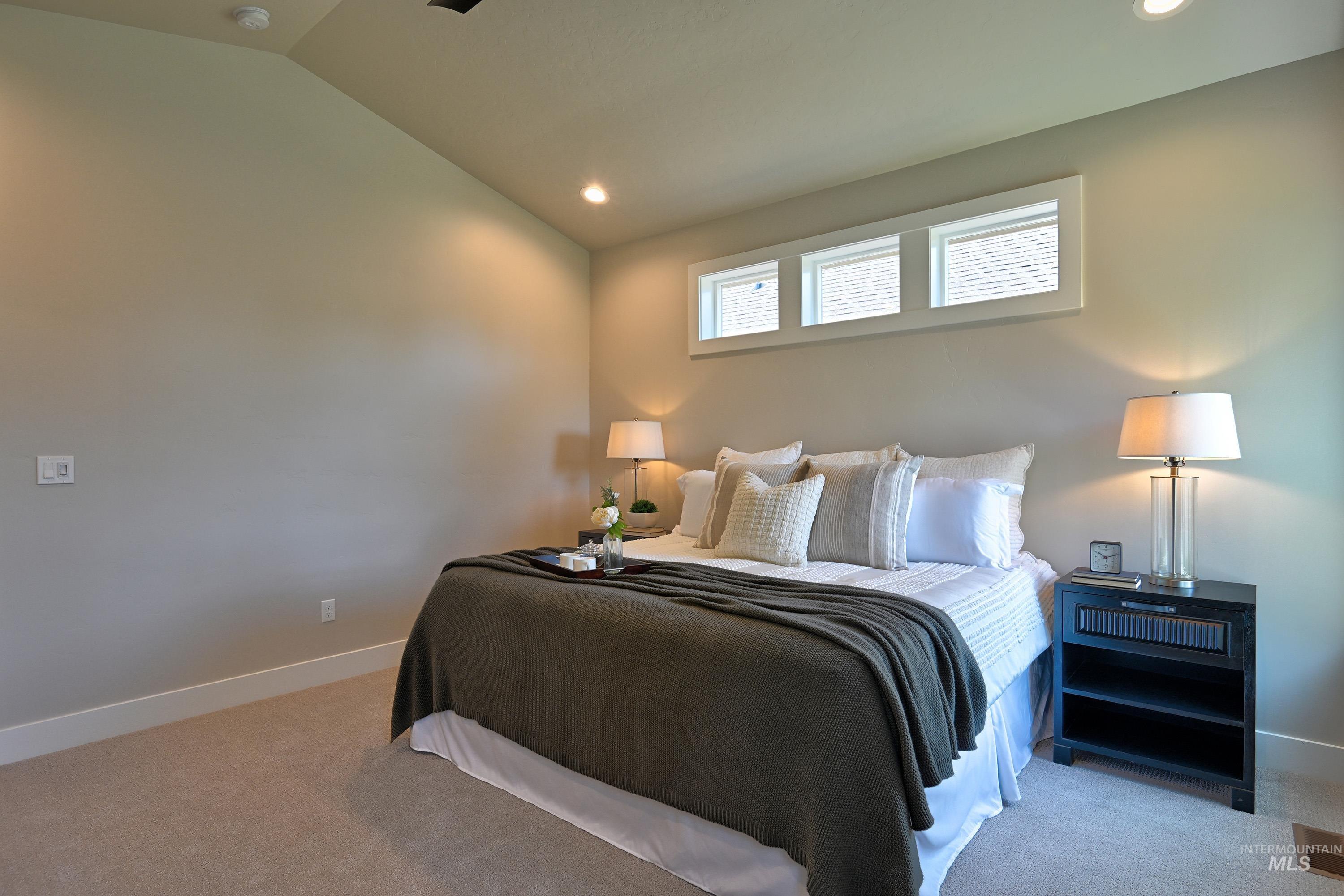 Carpeted bedroom with vaulted ceiling and recessed lighting