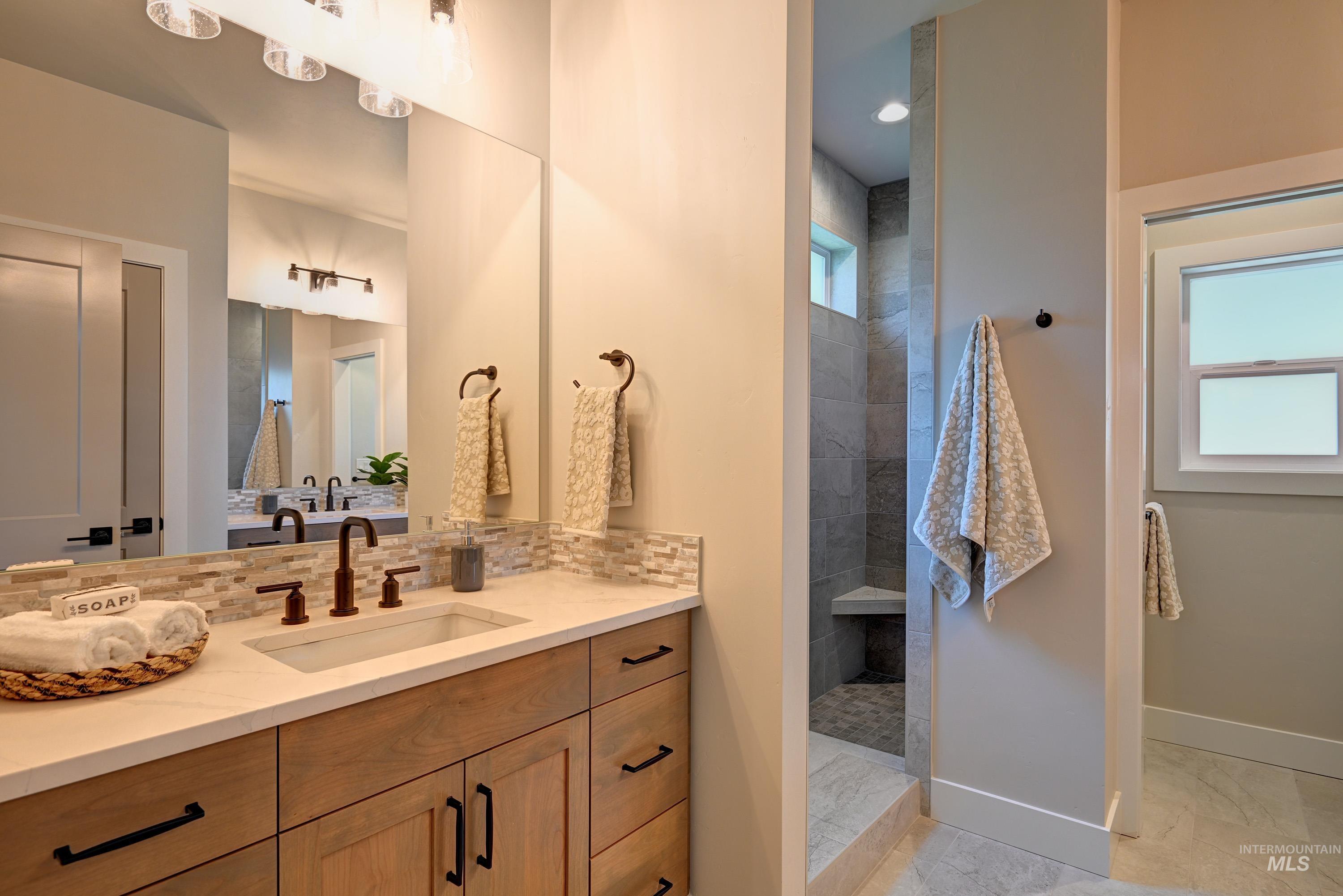 Bathroom featuring vanity, decorative backsplash, a walk in shower, and Tile finish flooring