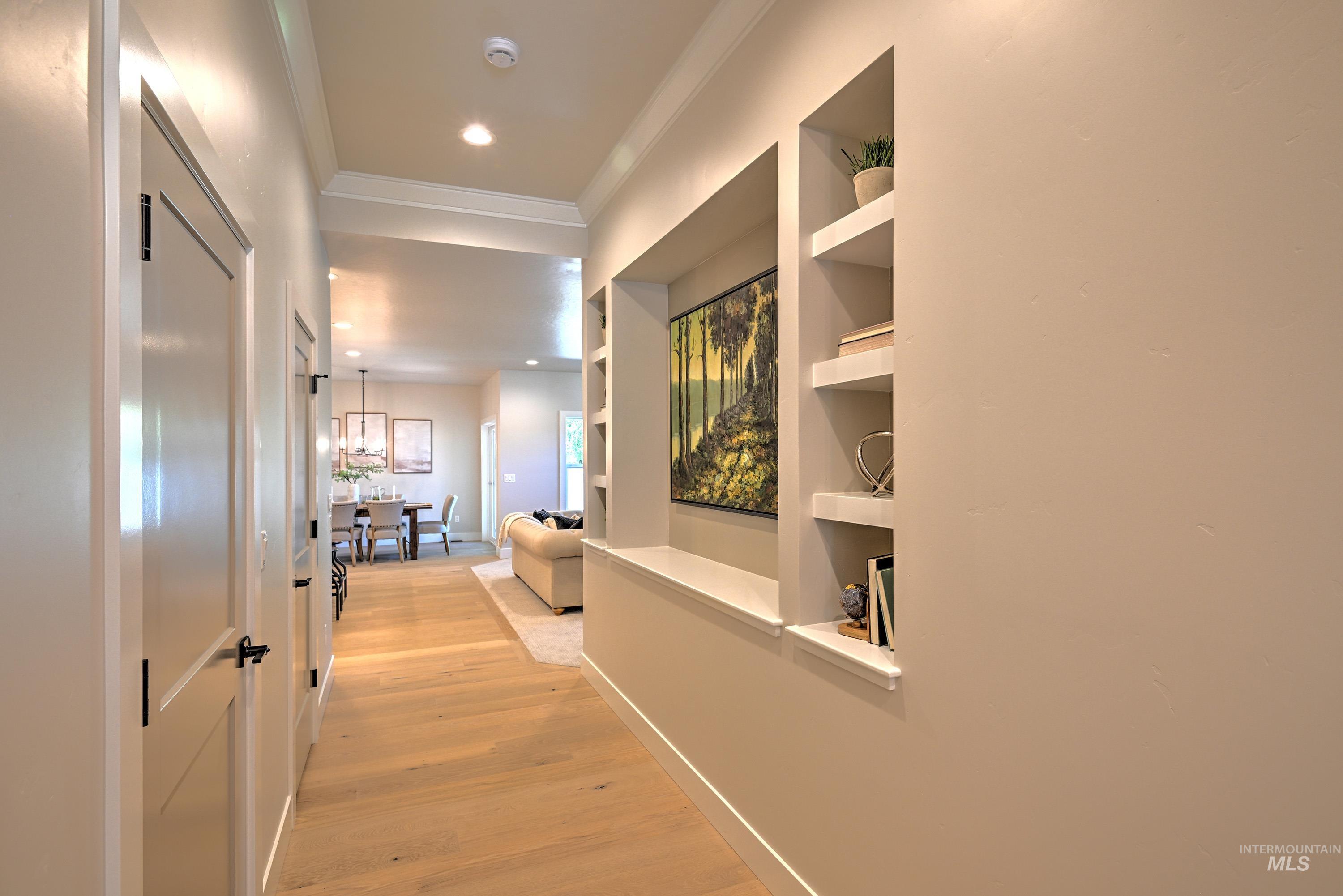 Hall featuring light wood-type flooring, crown molding, recessed lighting, and built in features
