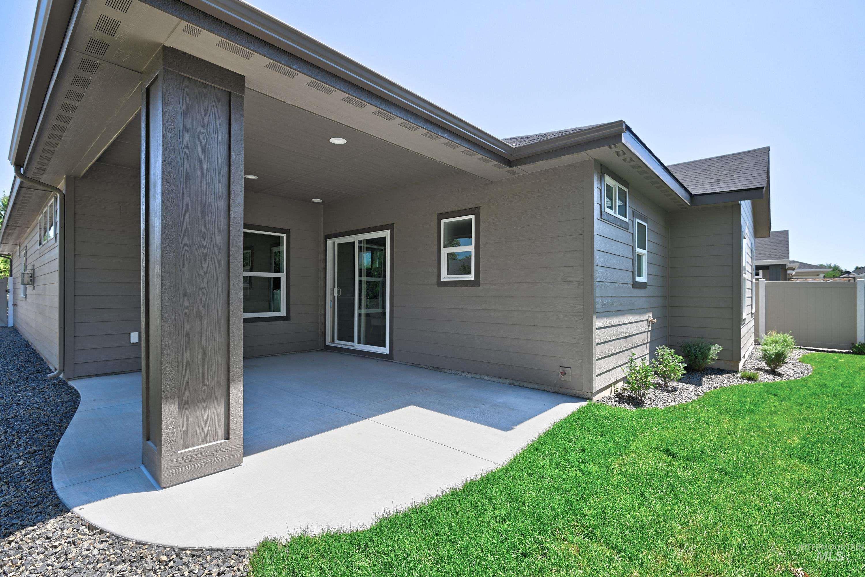 Back of house featuring a patio area and roof with shingles