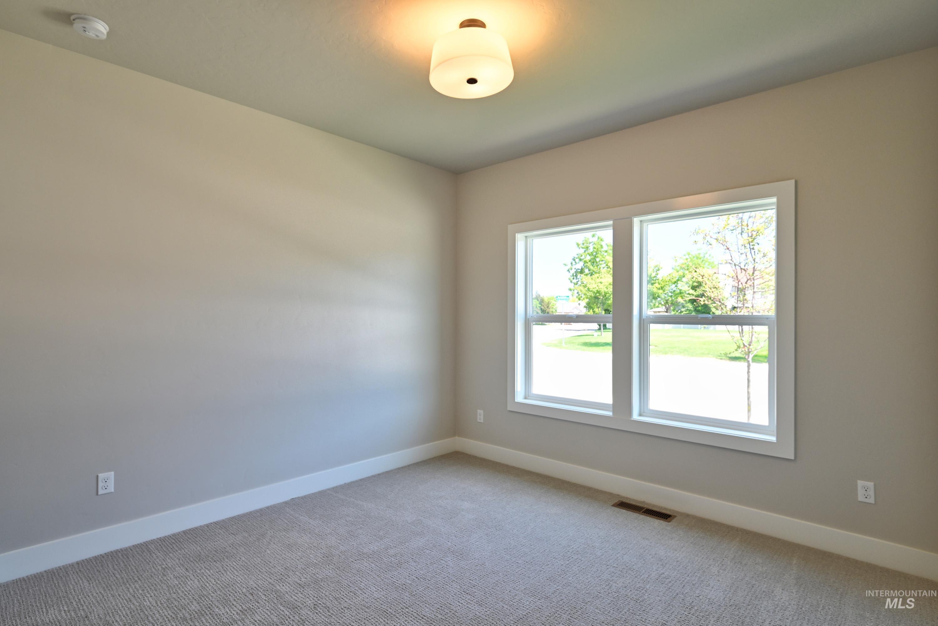 Spare room featuring light carpet and a smoke detector