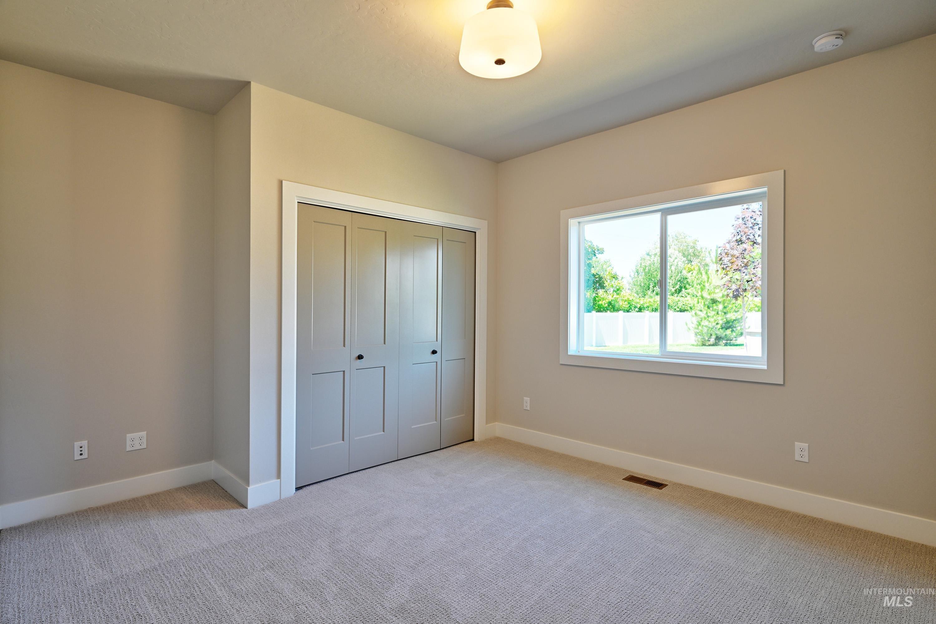 Unfurnished bedroom with light colored carpet and a closet