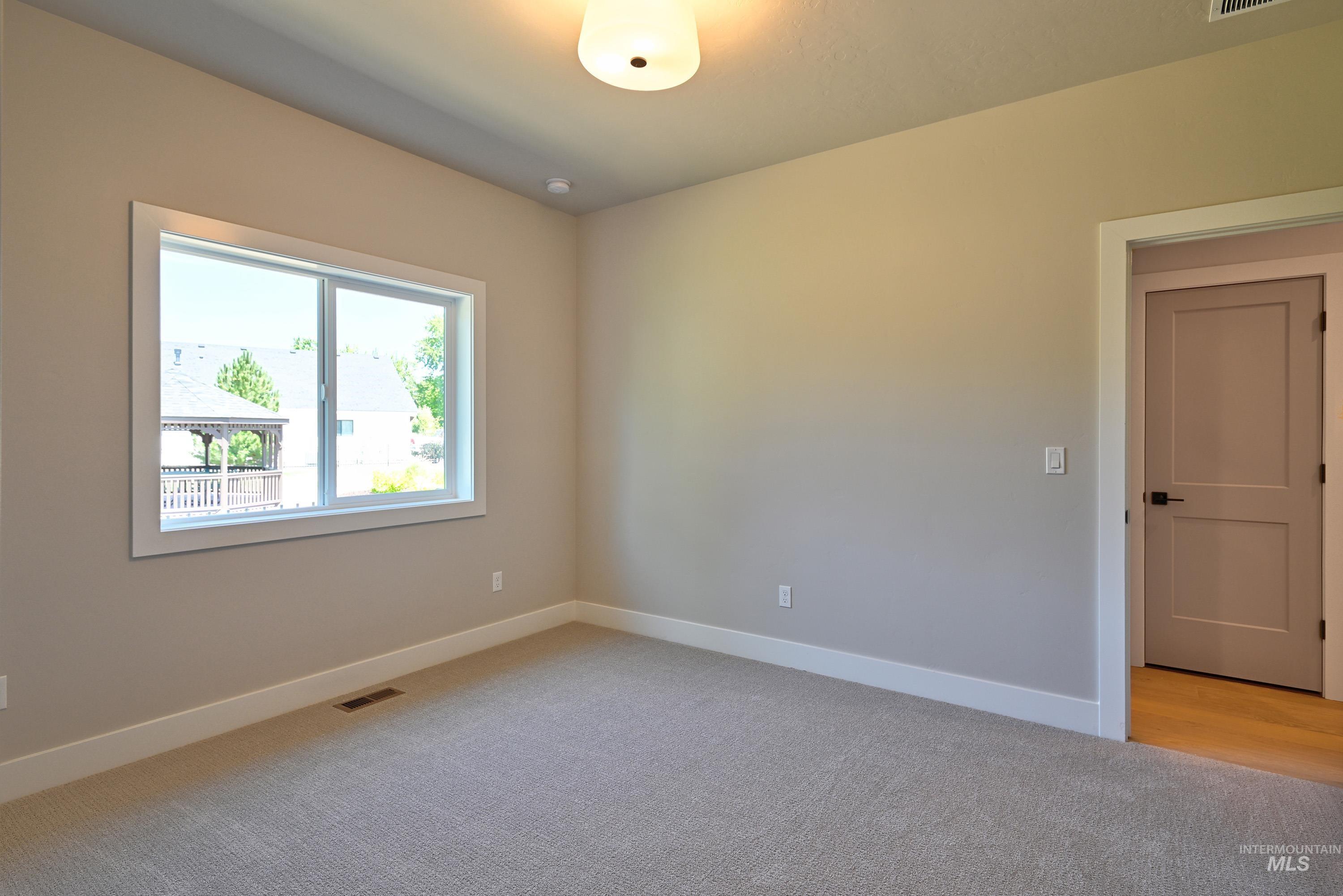Spare room with light carpet and baseboards