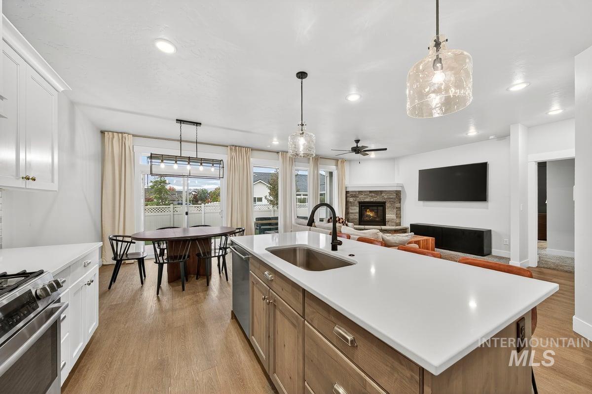 Kitchen featuring stainless steel appliances, a fireplace, pendant lighting, open floor plan, and recessed lighting