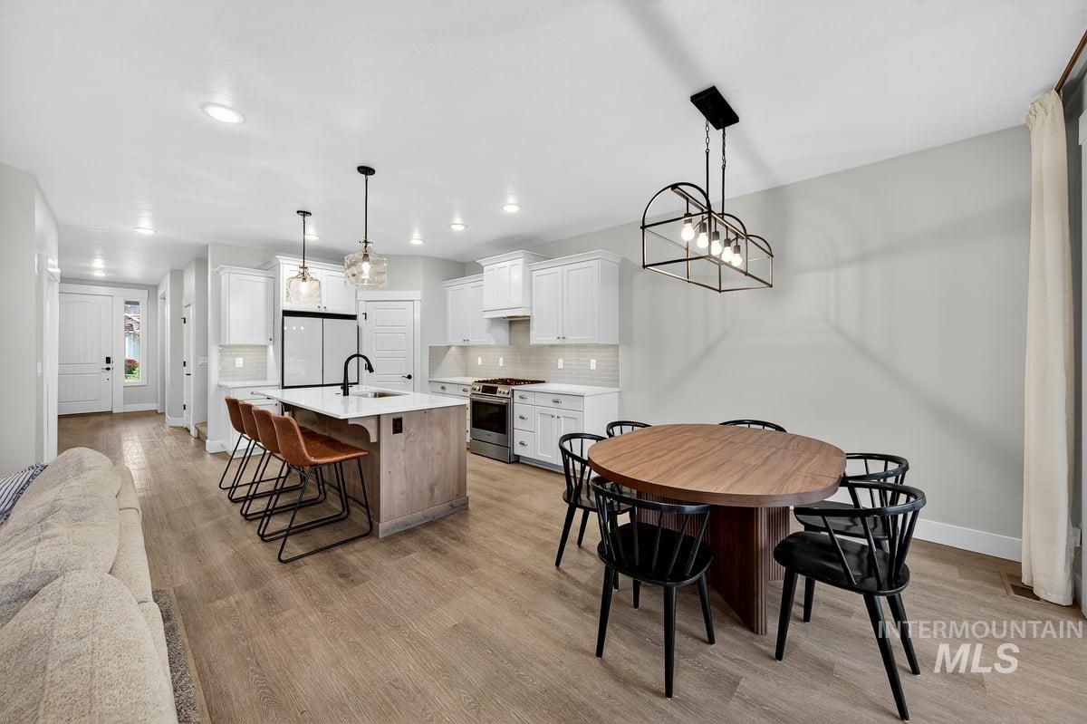 Dining space with a chandelier, light wood-style flooring, and recessed lighting