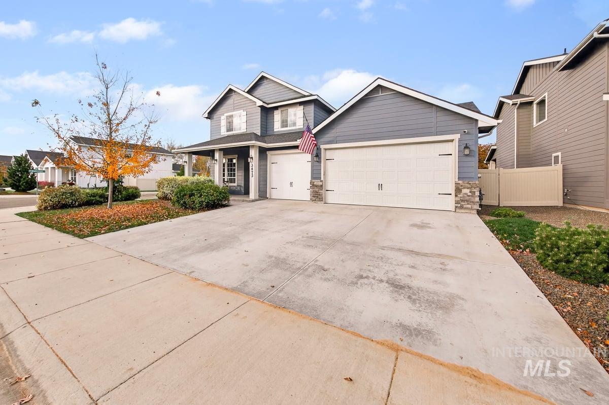 Traditional home featuring concrete driveway, stone siding, and an attached garage