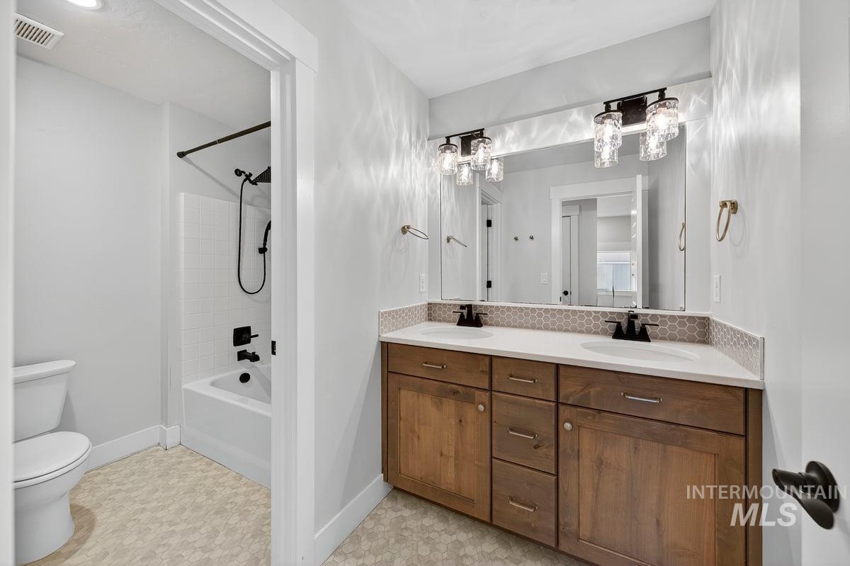 Full bathroom featuring double vanity, shower / bath combination, and backsplash