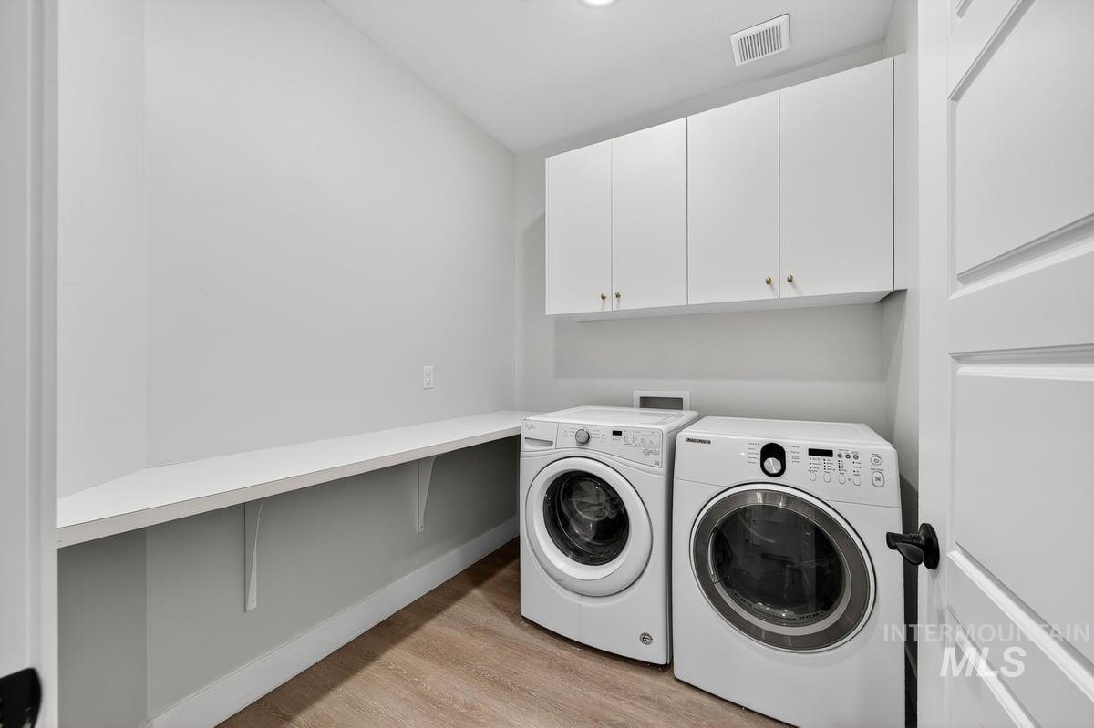 Washroom featuring light wood-style floors, cabinet space, and independent washer and dryer