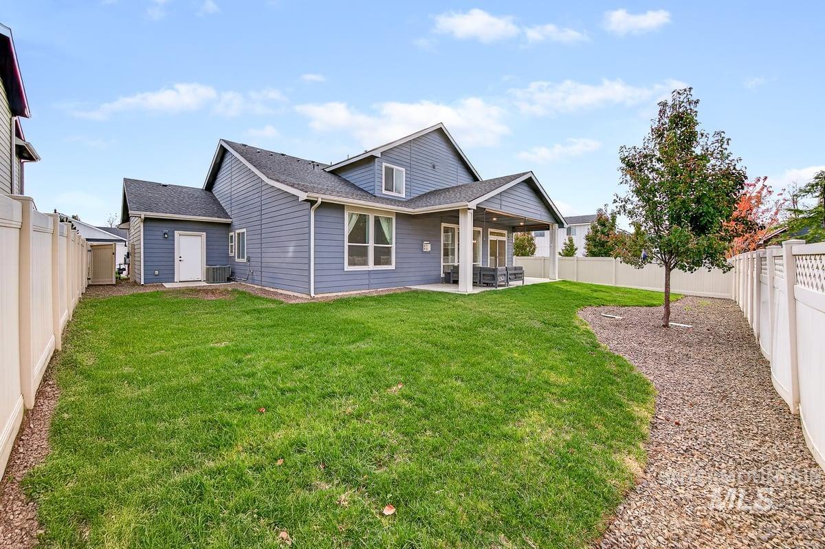 Rear view of property featuring a fenced backyard, a shingled roof, and a patio