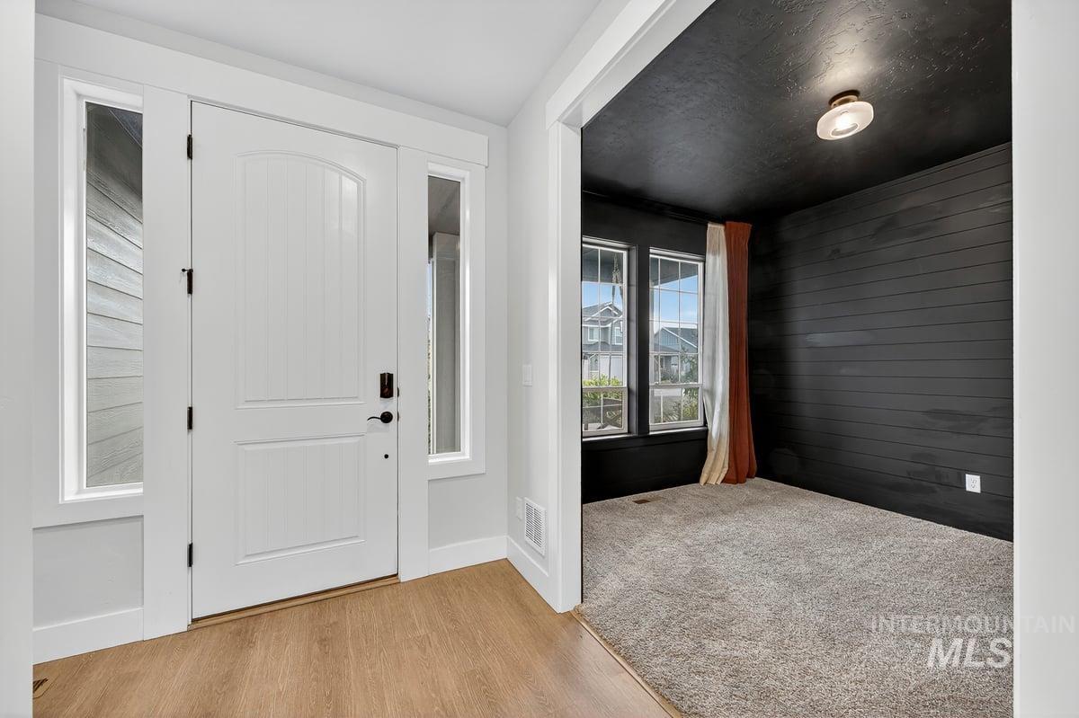 Foyer entrance featuring wood walls and light wood-type flooring