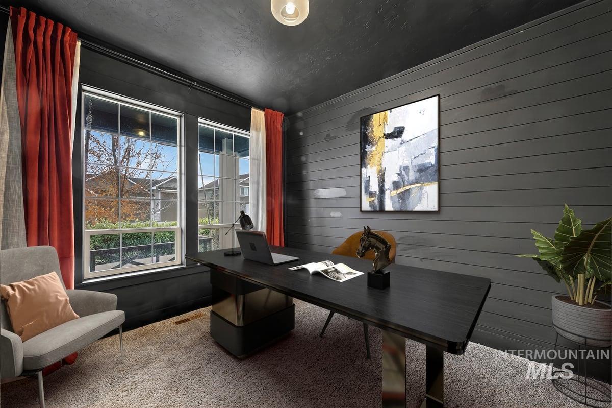 Carpeted home office featuring wooden walls