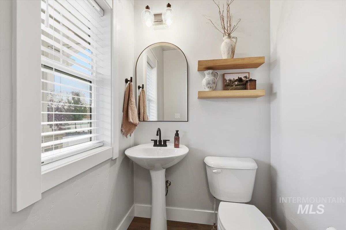 Half bathroom with toilet and dark wood-style flooring