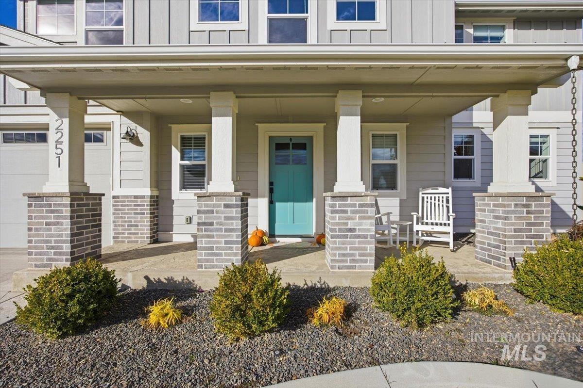 Entrance to property with board and batten siding, a garage, and covered porch