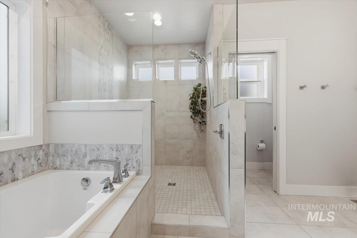 Bathroom with a garden tub, plenty of natural light, a tile shower, and light tile patterned flooring