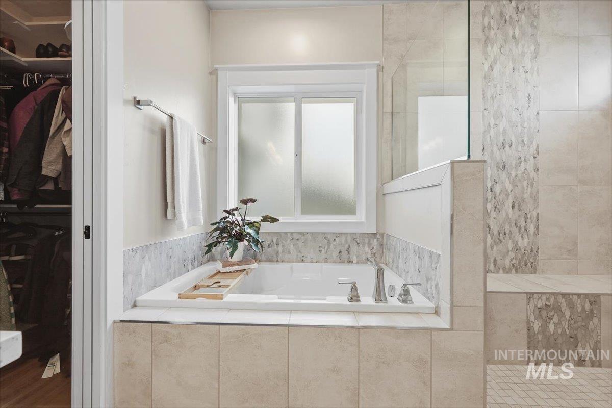 Bathroom featuring a walk in closet, a bath, and a walk in shower