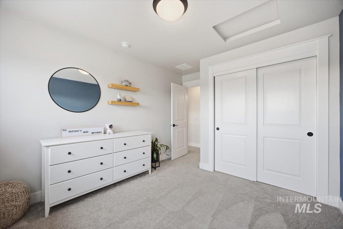 Bedroom featuring light carpet, a closet, and attic access