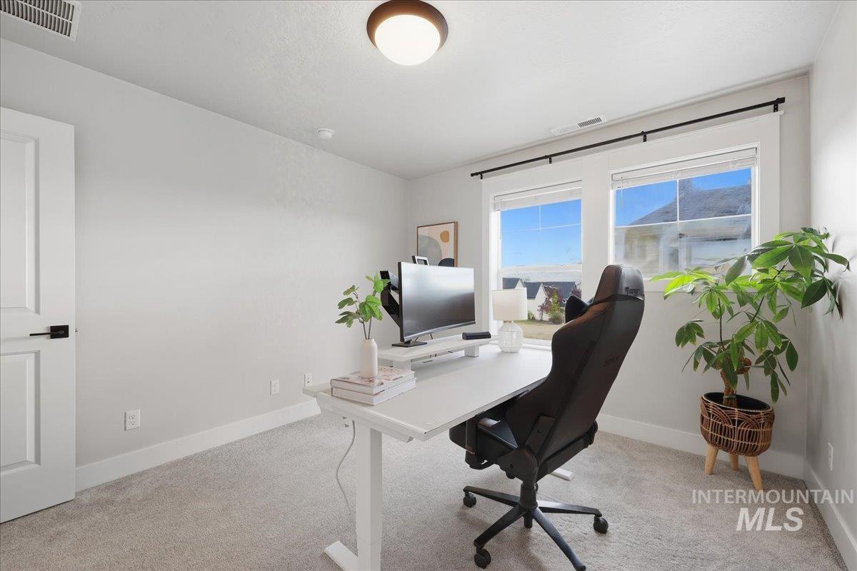 Office space with baseboards and light carpet