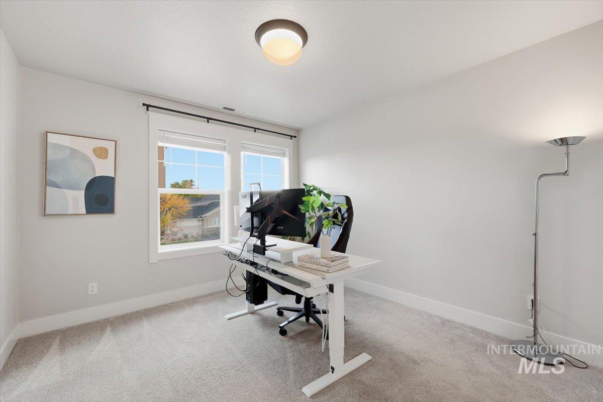 Home office with light colored carpet and baseboards